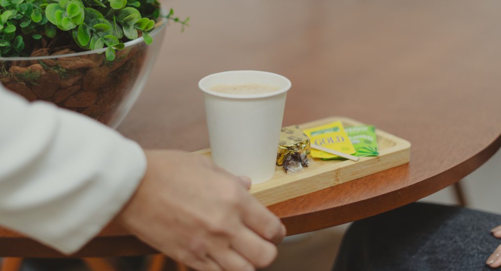 Mão alcança xícara de café na bandeja de boas-vindas da clínica