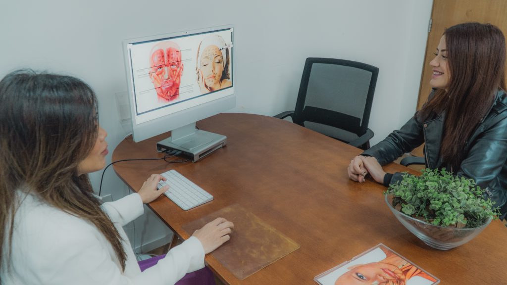 Dra. Juliana Toma aponta anatomia facial na tela durante a consulta