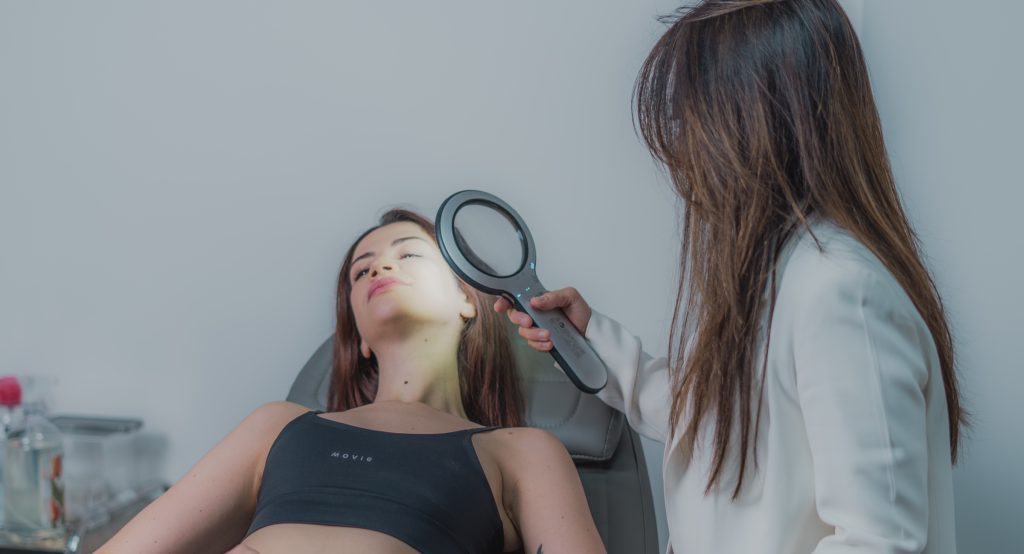 Exame da pele do rosto com lupa dermatológica iluminada