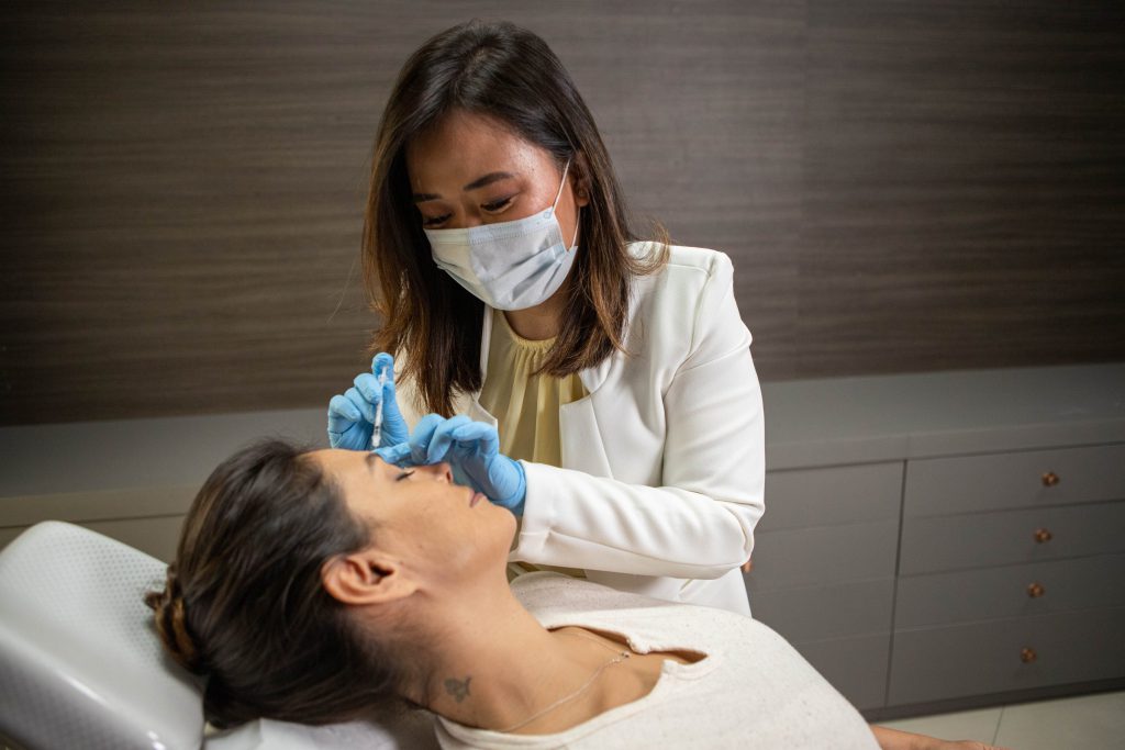 Dra. Juliana Toma aplica um injetável facial em paciente na maca