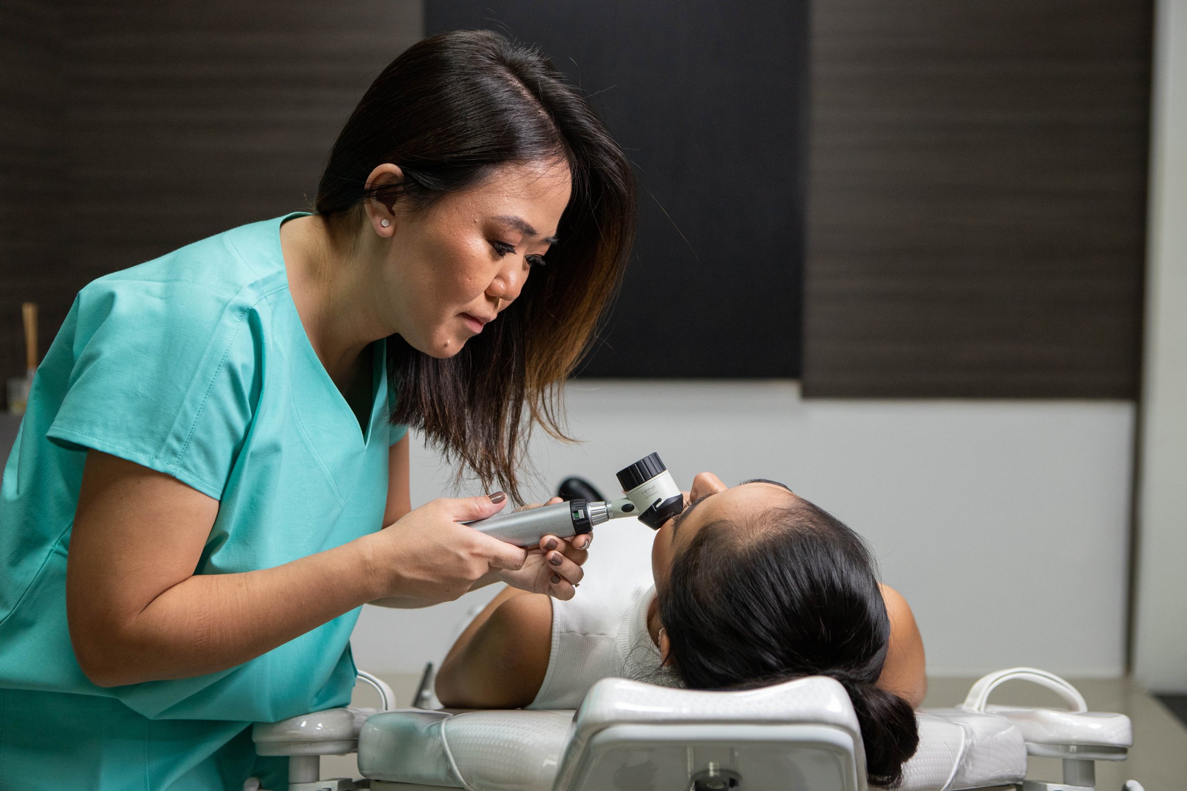Dra. Juliana Toma examina a linha do couro cabeludo com dermatoscópio.