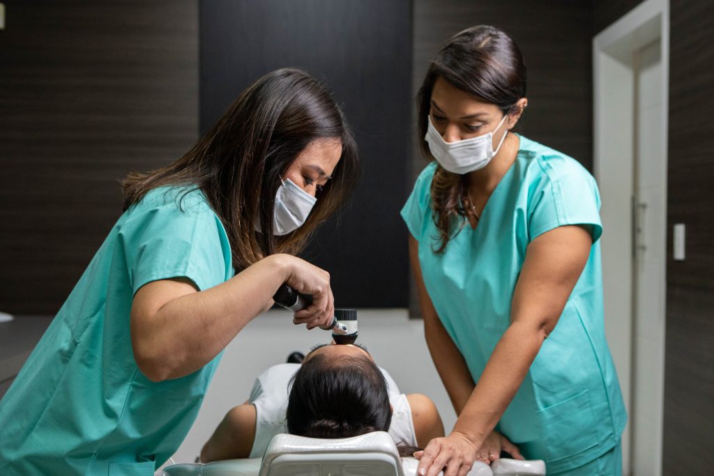 Exame do couro cabeludo com dermatoscópio, acompanhado pela equipe.